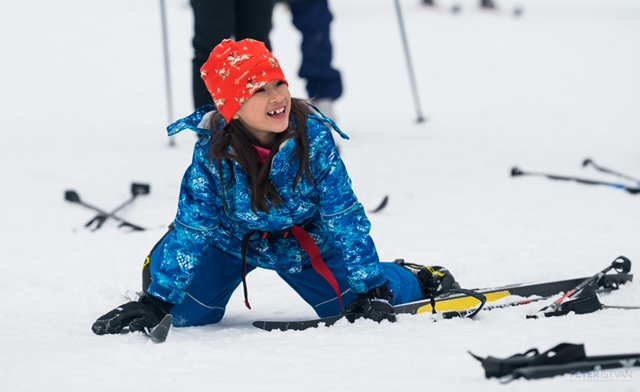 A Jackrabbit student smiles after falling over on her skis.
